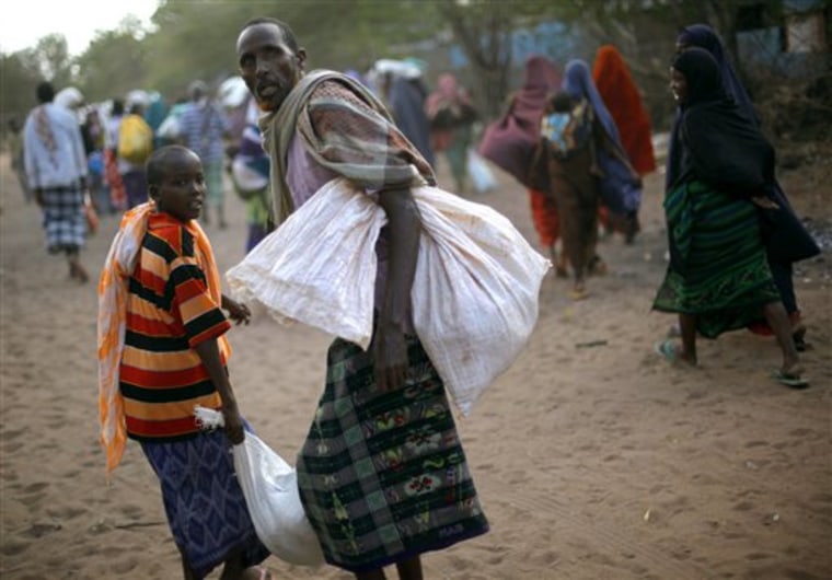 Somali refugees carry their donated rations of food aid in the  eastern Kenyan village of Hagadera near Dadaab, 100 kms (60 miles) from the Somali border, Sunday Aug. 7, 2011.  The drought and famine in the horn of Africa has  killed more than 29,000 children under the age of 5 years in the last 90 days in southern Somalia alone, according to U.S. estimates. The U.N. says 640,000 Somali children are acutely malnourished, suggesting the death toll of small children will rise. (AP Photo/Jerome Delay)